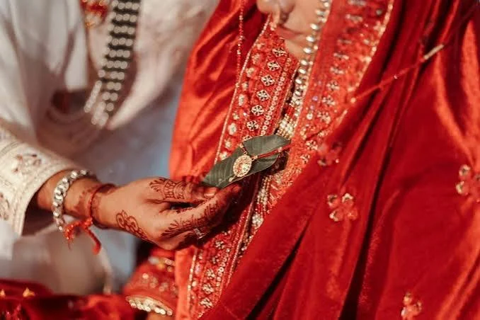 Hands of a bride and groom during a Vedic wedding ritual, the bride in red with mehendi